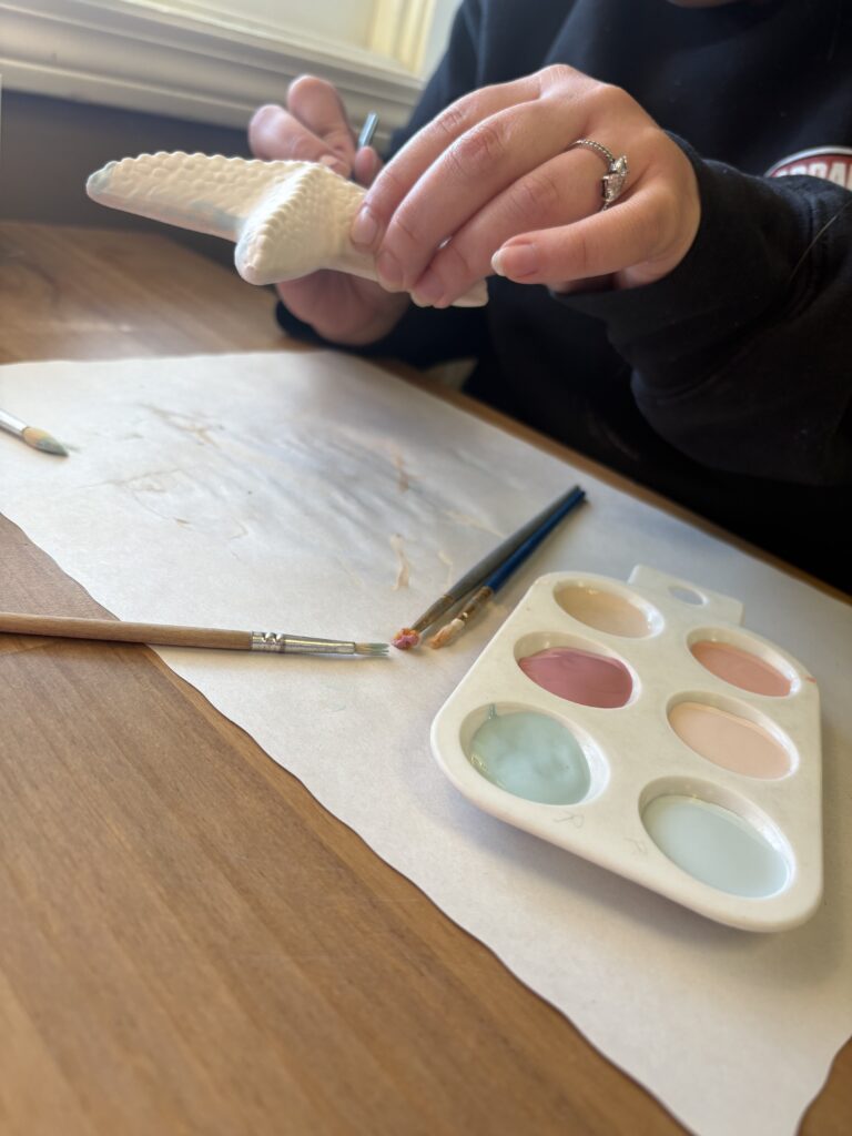 The starfish piece is being held up and being painted on the sides in light blue