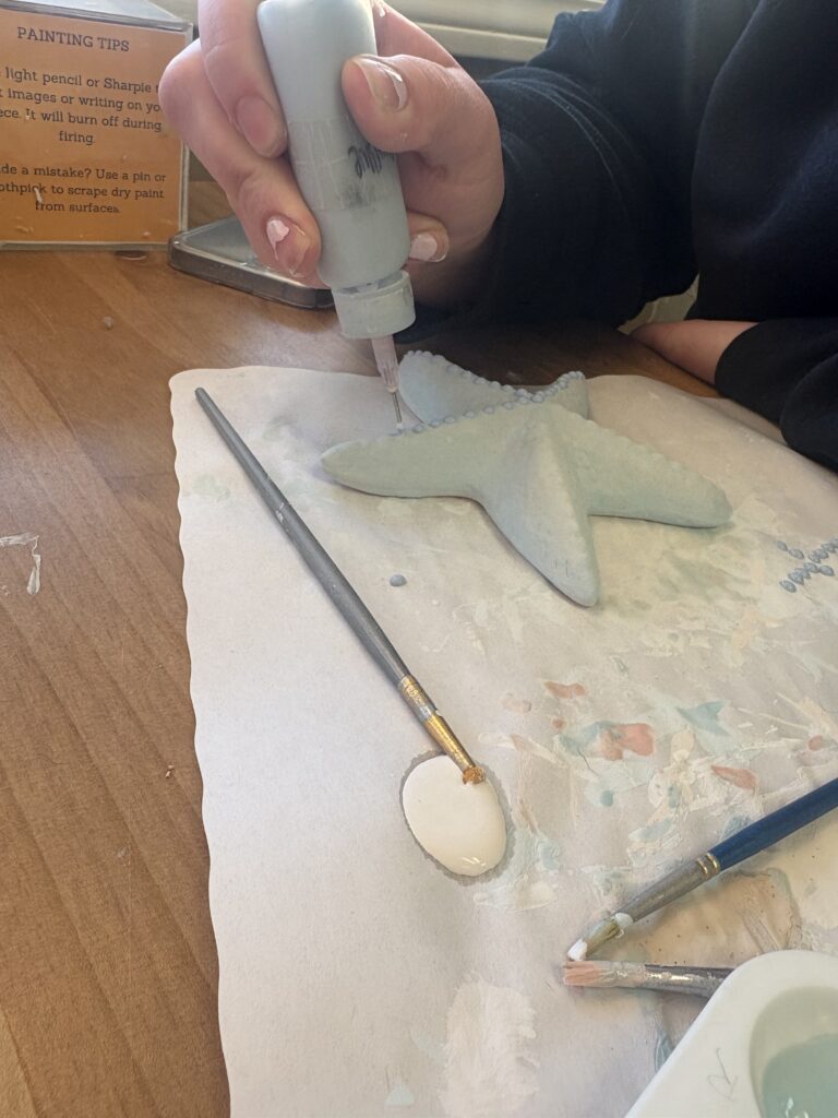 The light blue writing tool is being used to add light blue dots to the top of the starfish piece
