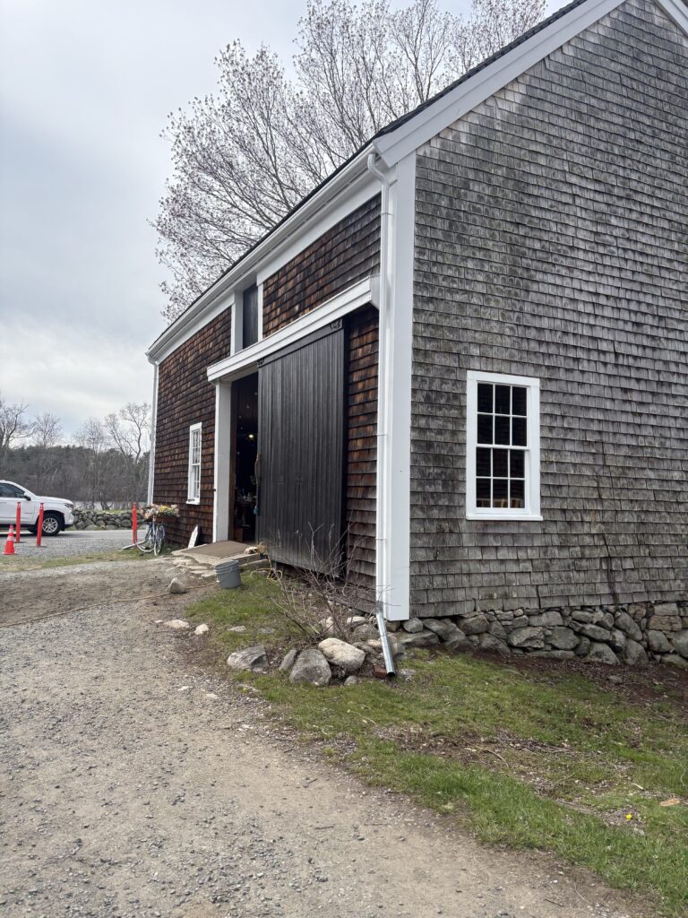 A barn with dark brown, wood shingle siding is shown
