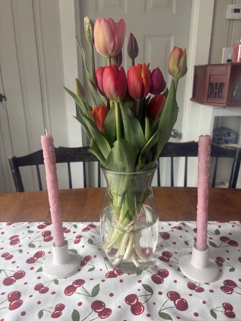 A vase of colorful tulips is shown on a table