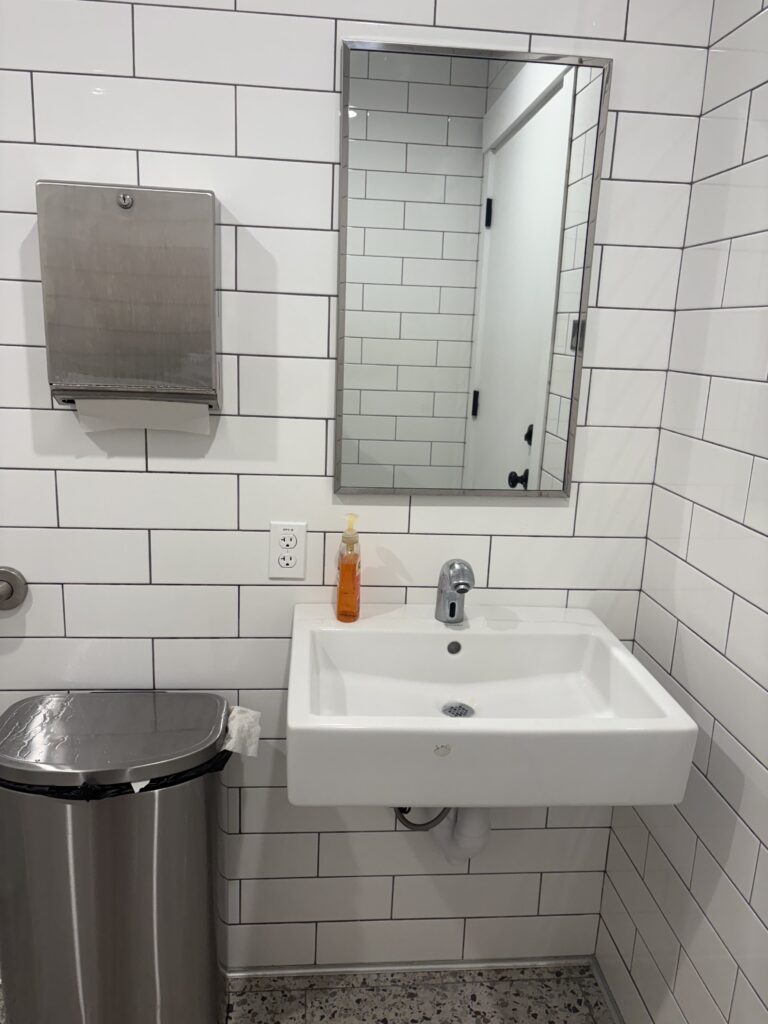 The sink is automatic but the orange soap bottle and metal paper towel dispenser are manual 
