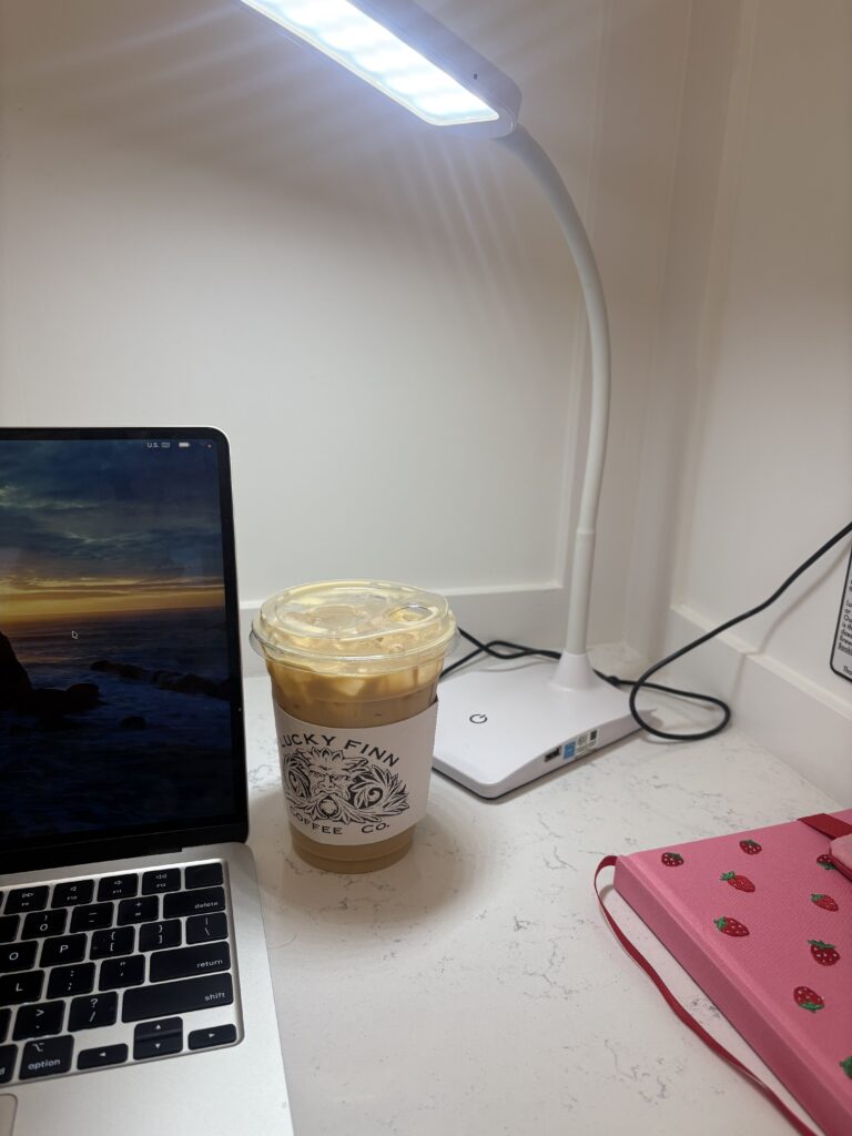 A Lucky Finn Cafe latte next to a laptop under a bright desk lamp