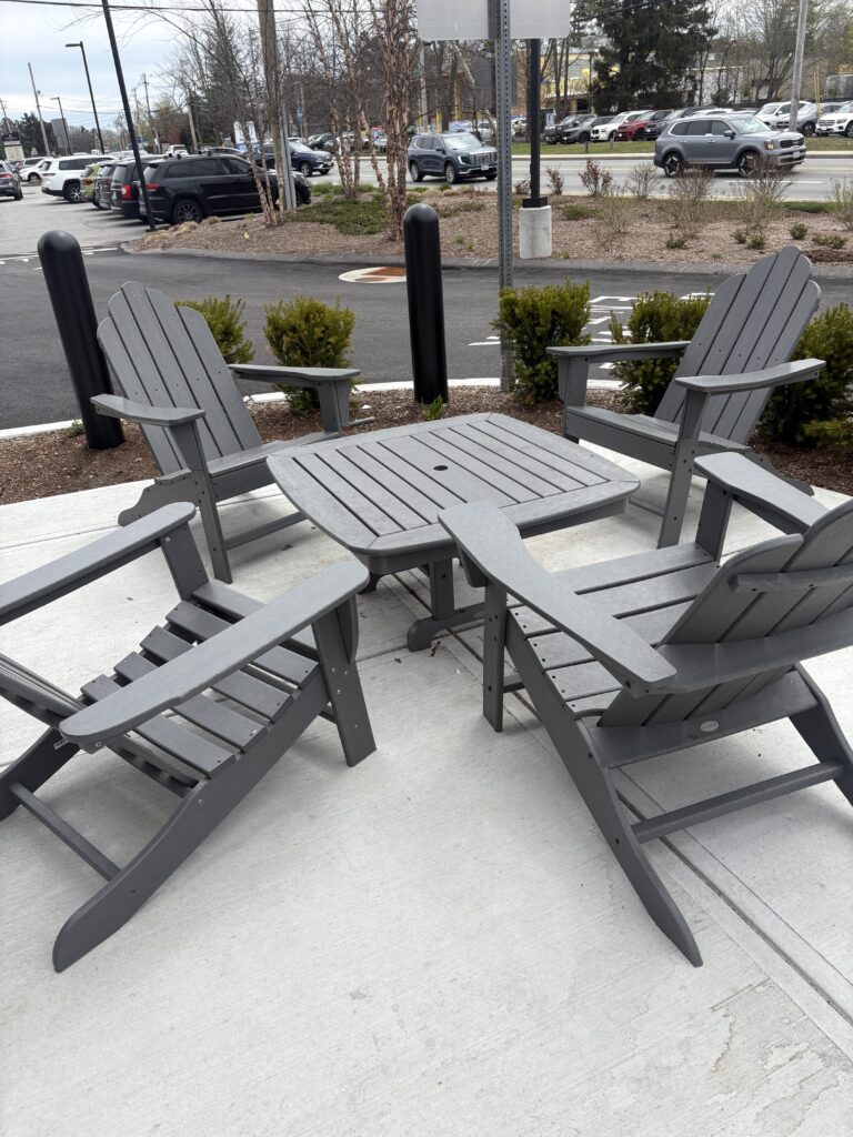 The outdoor seating area at Lucky Finn Cafe includes four grey Adirondack chairs and a grey square table 