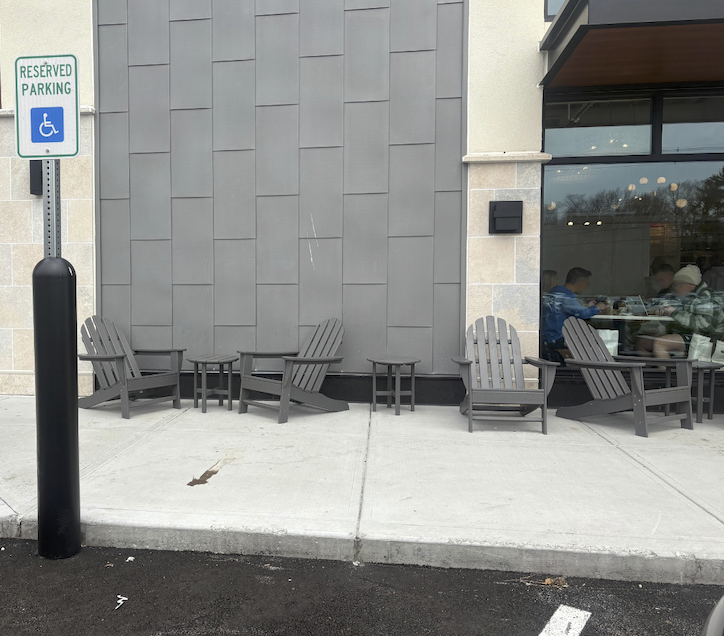 There are groups of two Adirondack chairs with a very small round table between them lining the front of the Lucky Finn Cafe
