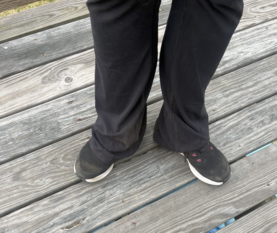 A person's black pants and black shoes that are covered in brown dust are shown