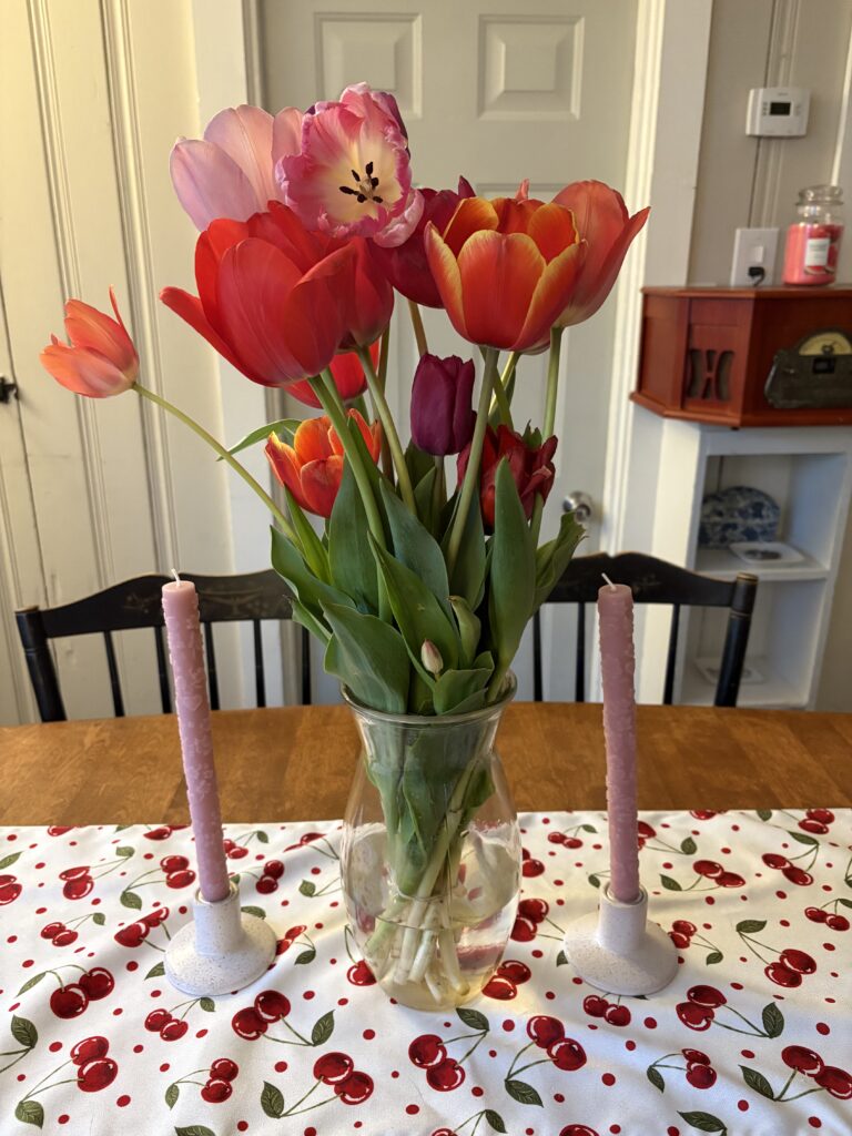 A vase of colorful and fully bloomed tulips is shown on a table