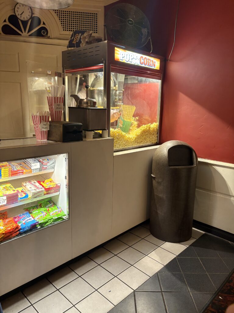 Popcorn is in a popcorn case with an employee scooping some into a bag