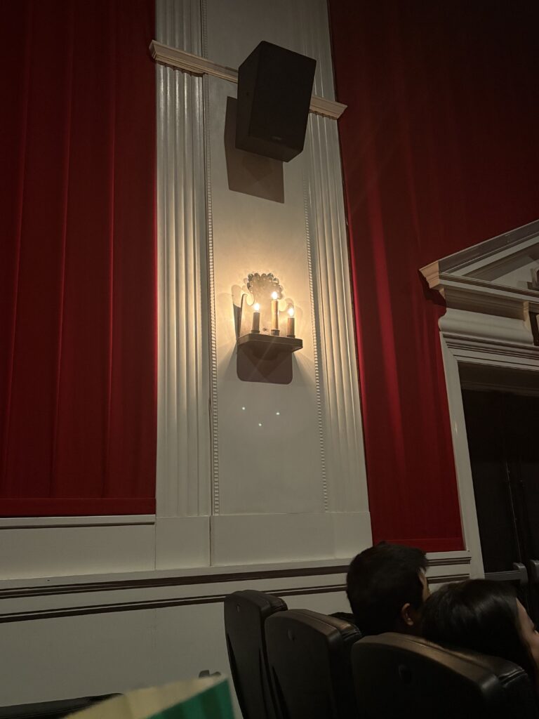 A theater stereo box is shown above a sconce with three faux candles