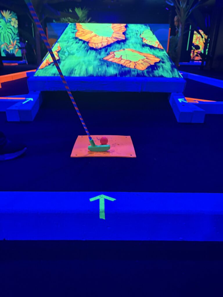 A person is putting a pink ball into a neon green tunnel