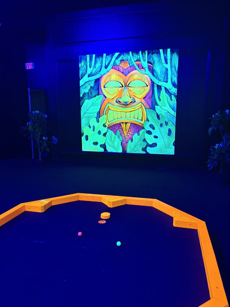A mural of a tiki figure is facing the course