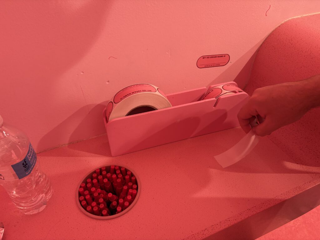 Name tags and red pens sit on a pink desk