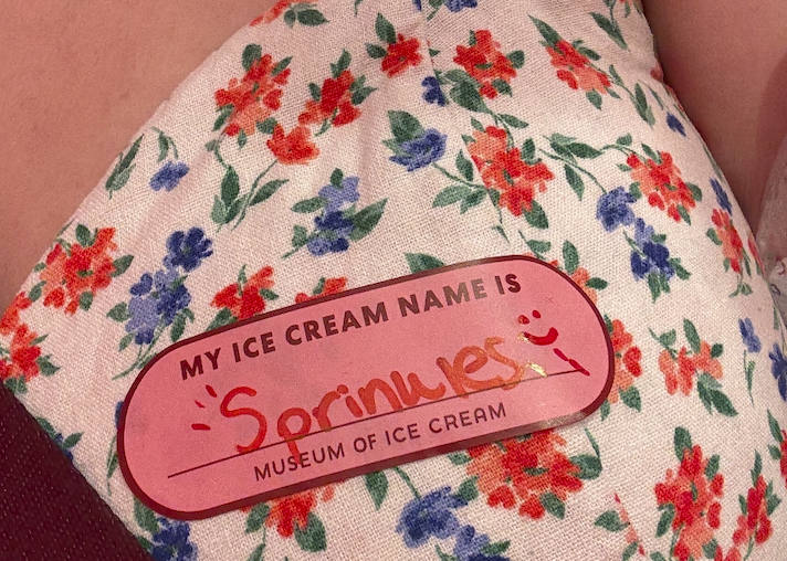 A name tag on a women's dress that says "Sprinkles"